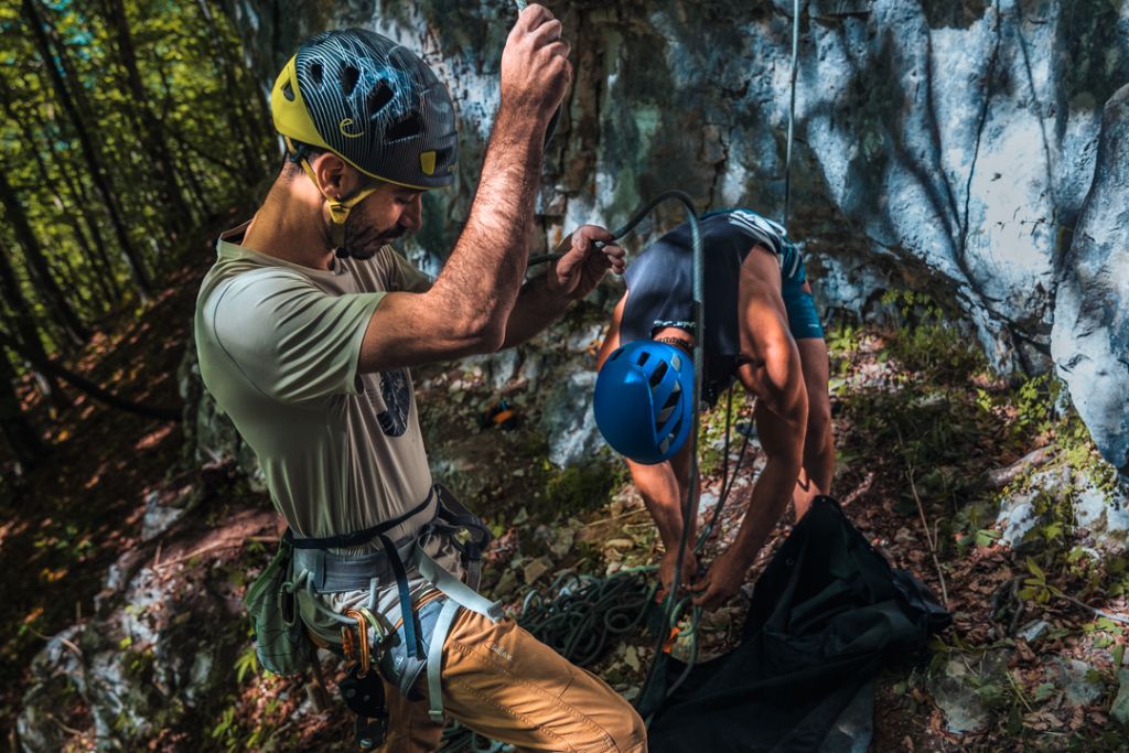 Arrampicatore con casco fa sicura alla base della parete