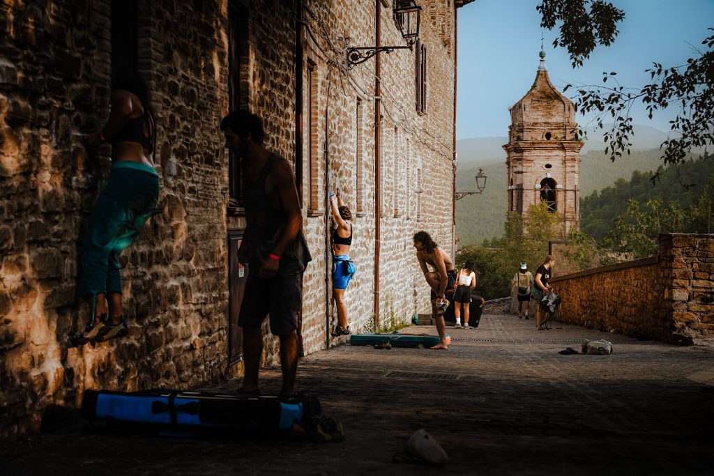 Arrampicatori sui muri del borgo con il campanile sullo sfondo