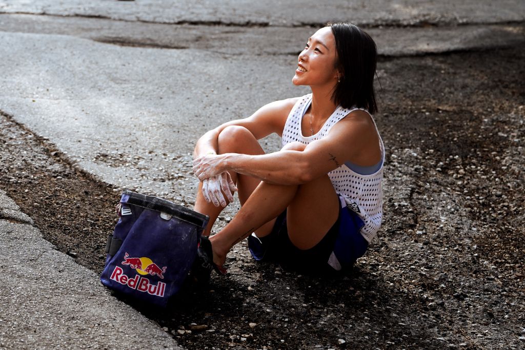 Jain Kim seduta in strada accanto al sacchetto Red Bull