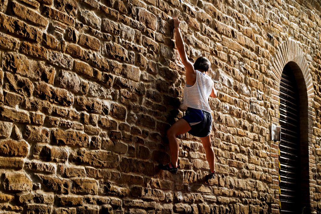 Jain Kim arrampica sul muro in pietra accanto al portone