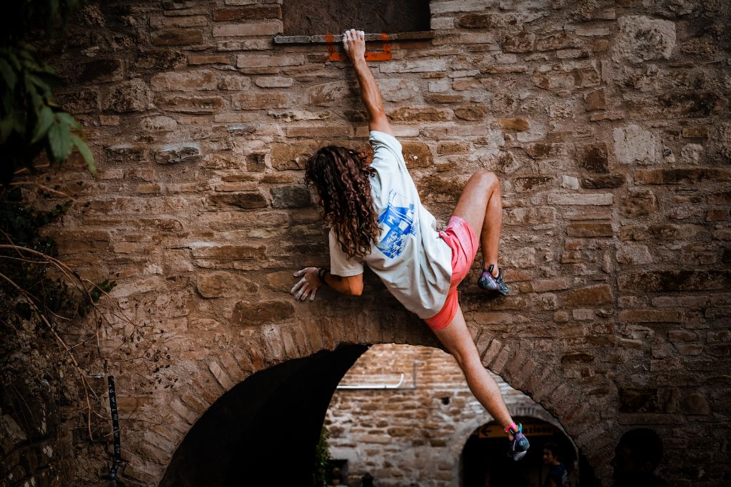 Arrampicatore in spaccata sopra l’arco del borgo