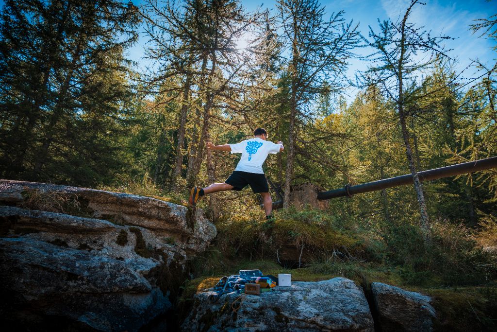 Salto tra i massi nel bosco di larici con la maglia Lazy Ghost